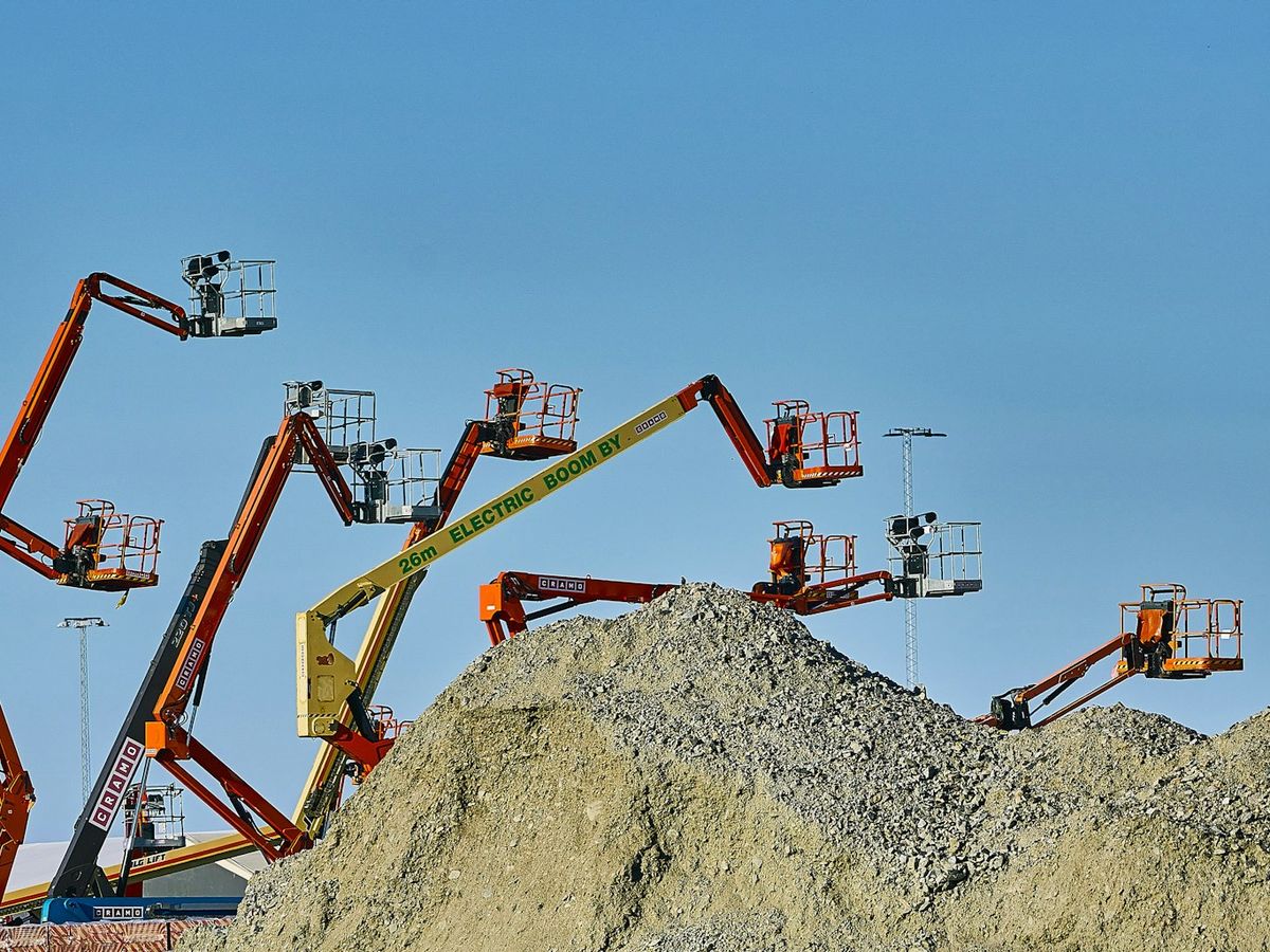 Boom lifts raised behind a gravel pile
