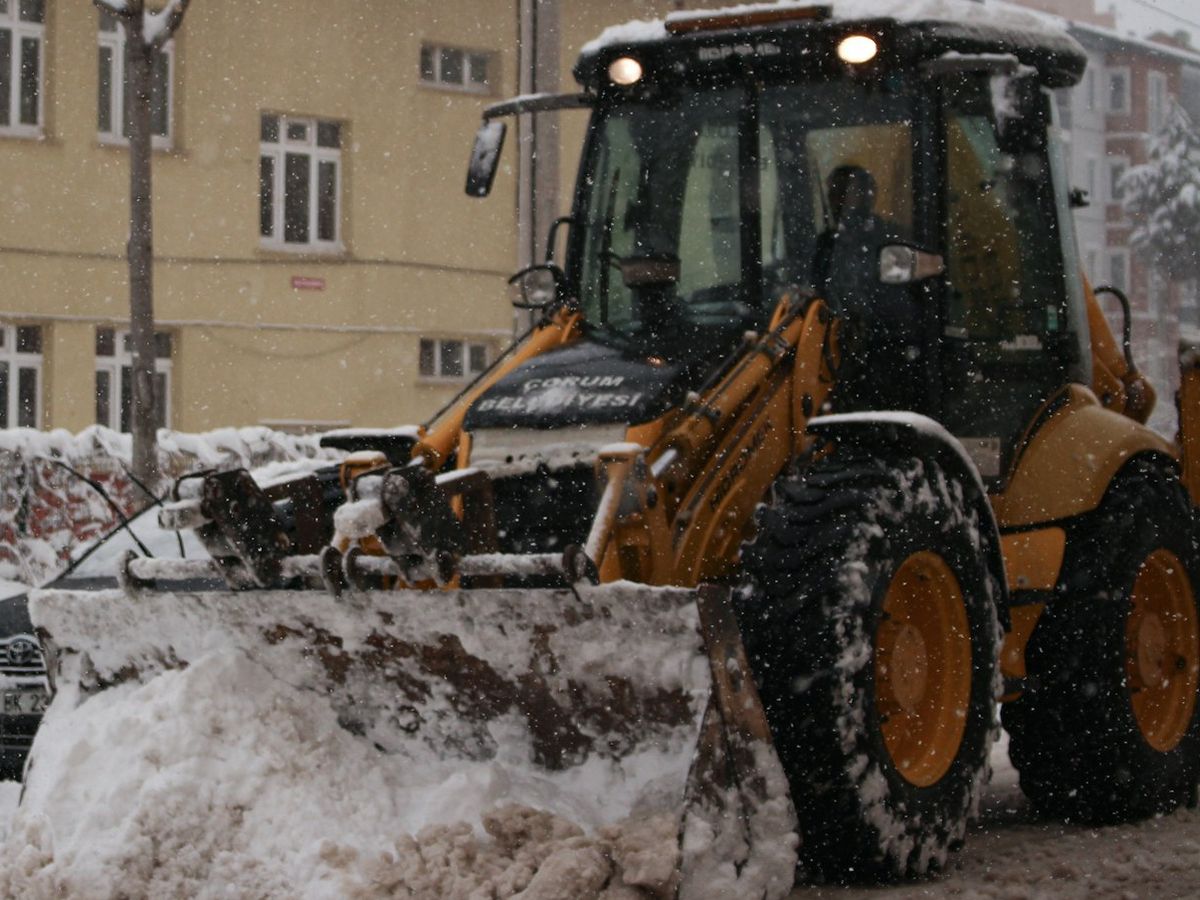 Backhoe loader clearing snow on a city street