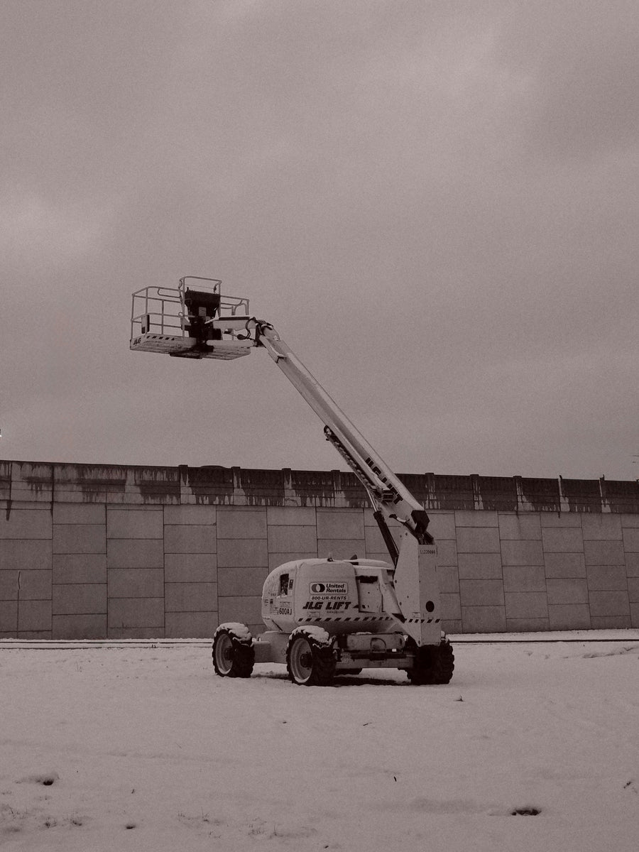 Boom lift parked in snow on a grey winter day